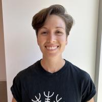 Petite woman with short hair cut, smiling, wearing dark graphic tee