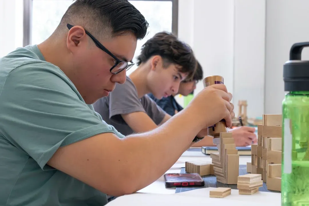 a photo of three male high students building their architecture models