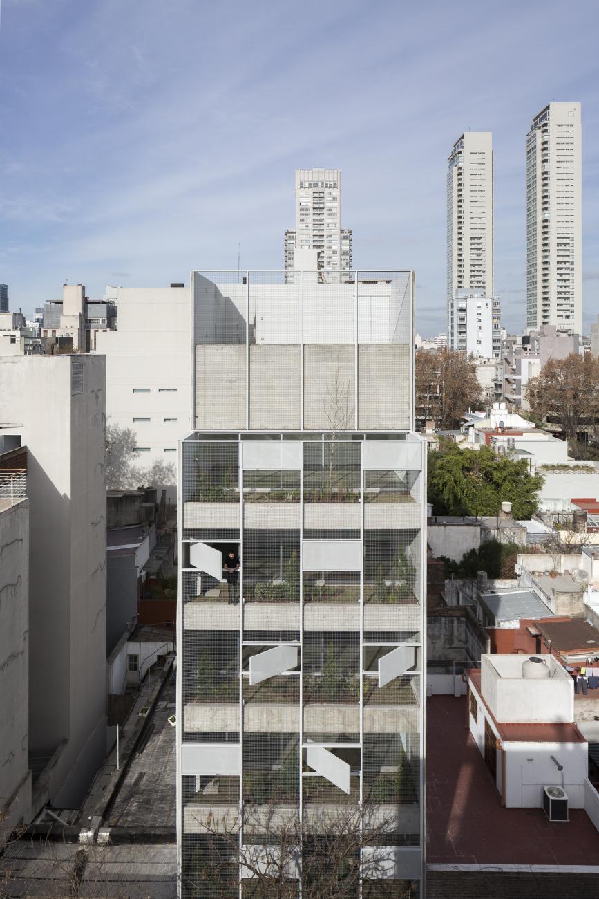 White multistory building with a porous facade.