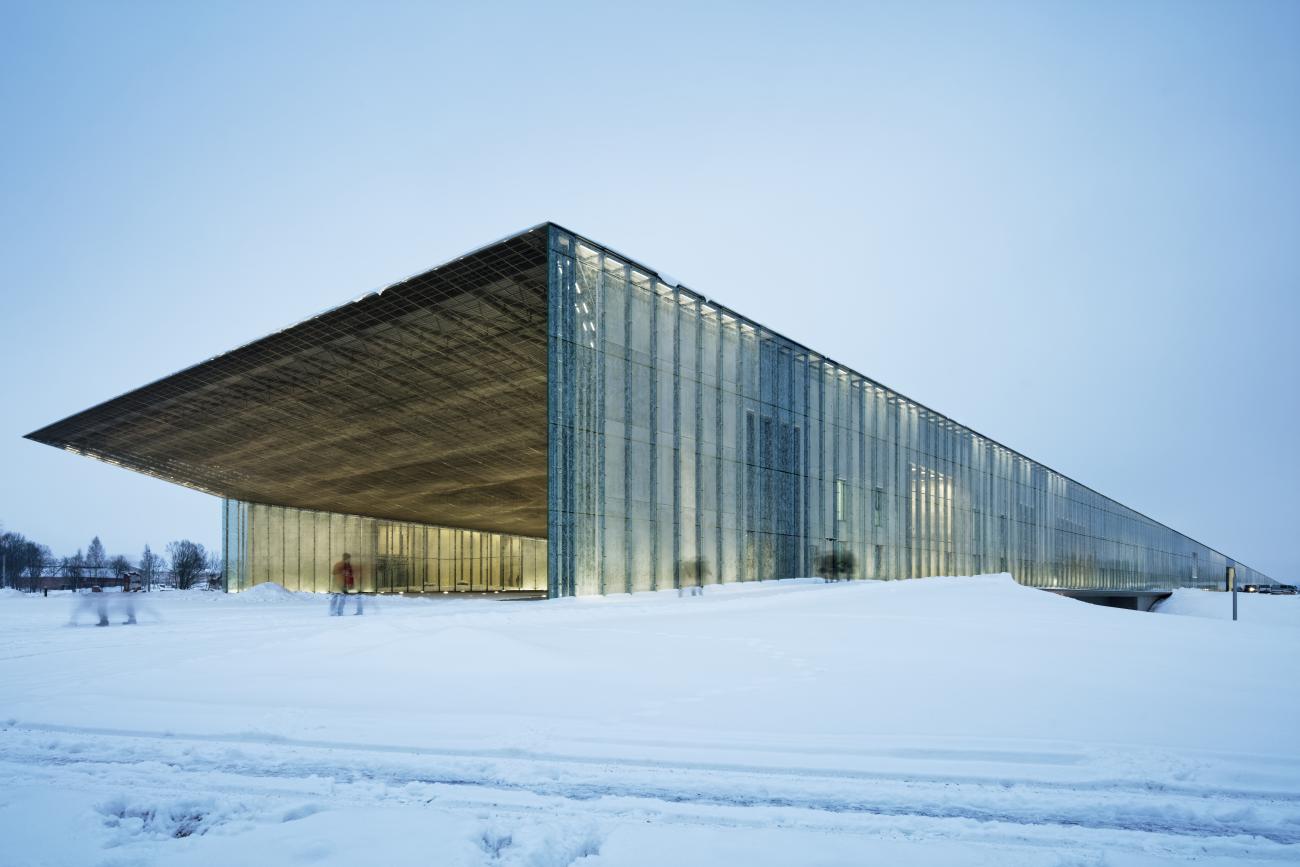 A large glass shed-like building sits in a snowy landscape.