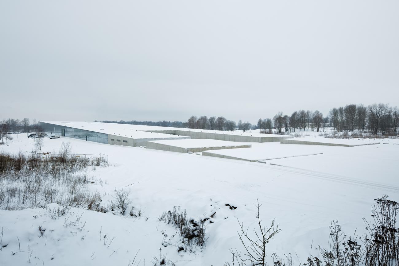 A large glass shed-like building sits in a snowy landscape.