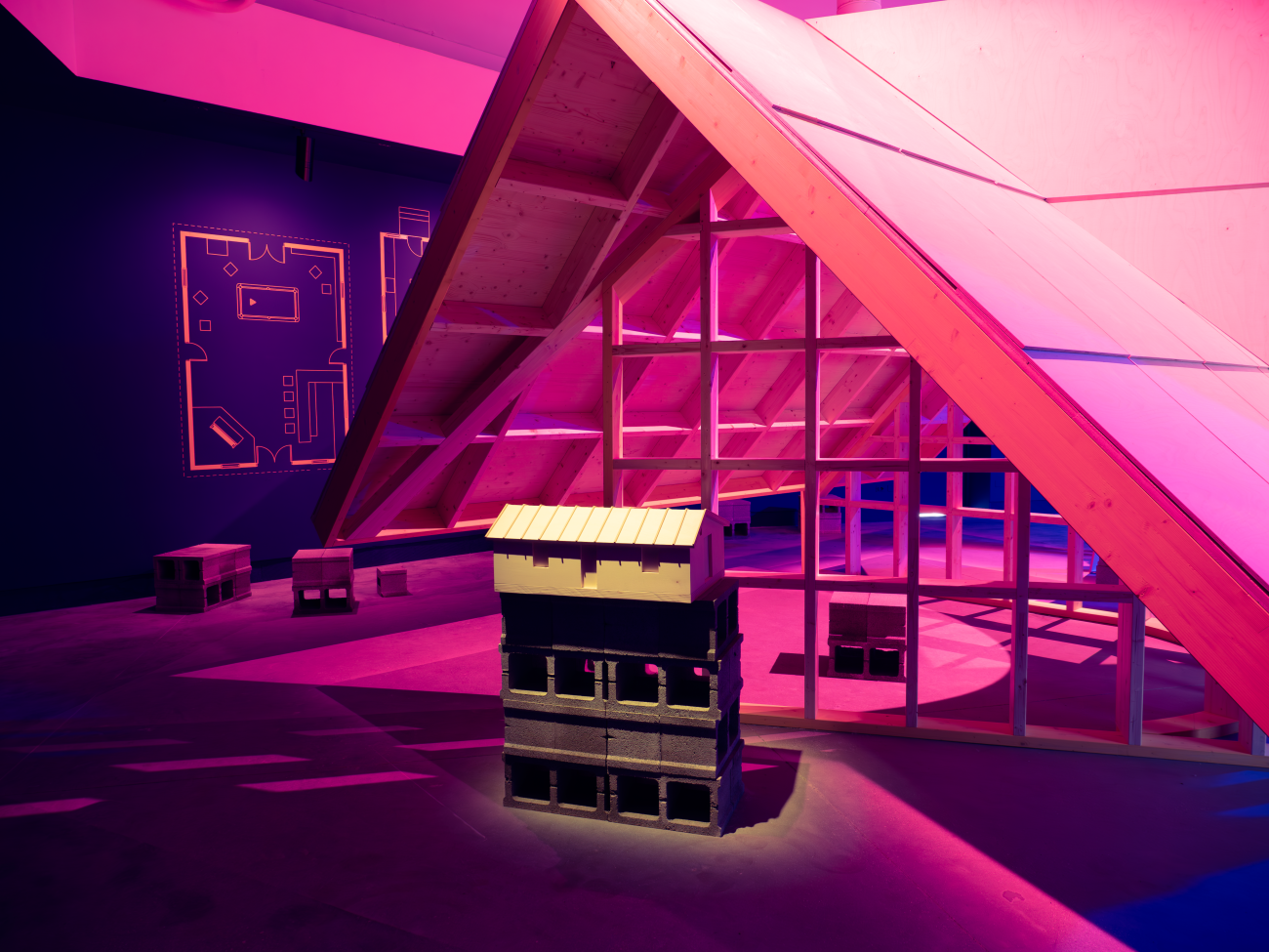 Steep pitched roof structure in an interior space with purple and magenta lighting