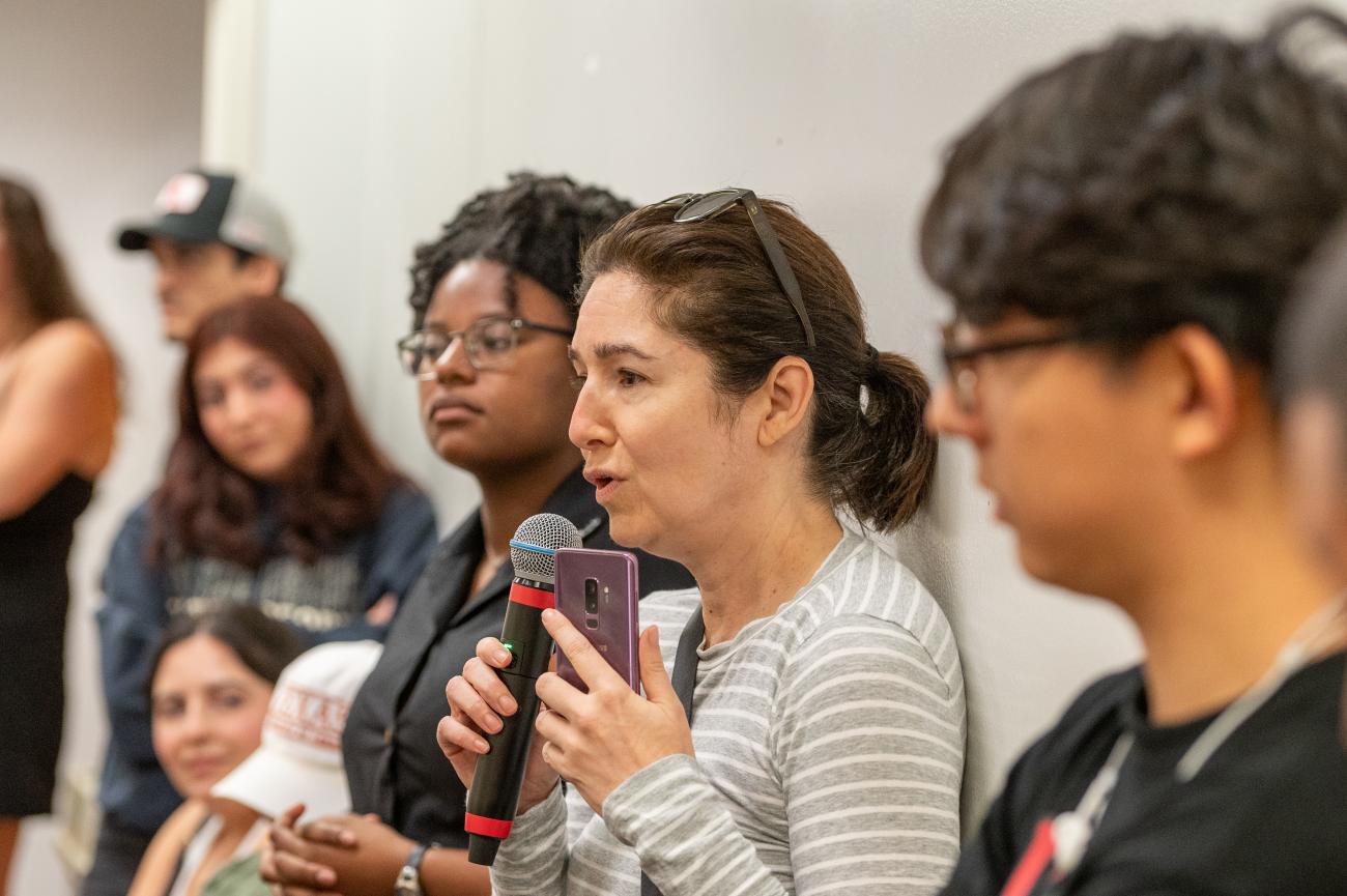 photo of young woman holding the microphone addressing the crowd