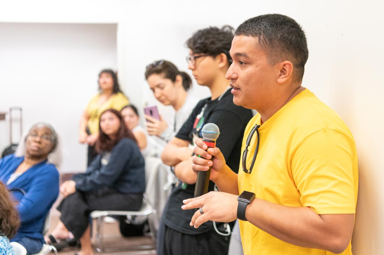 photo of young man with microphone addressing the room