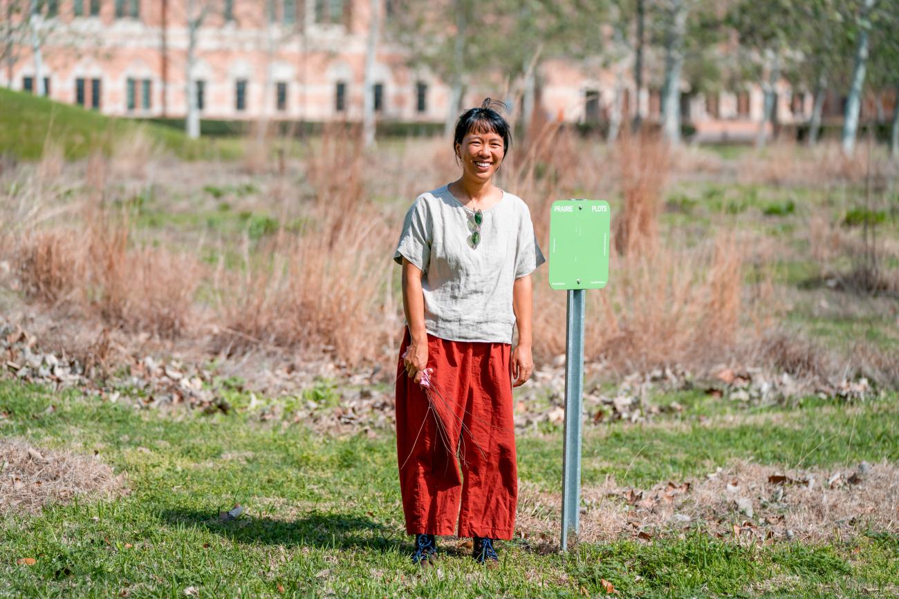 Image of Asst Professor Maggie Tsang standing in front of her prairie plot on campus
