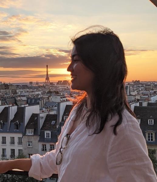 photo image of side profile of young woman with view of Eiffel tower in the far background framed by a beautiful sunrise