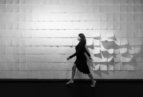 Woman walking by paper wall